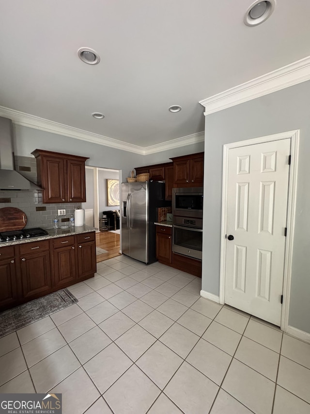 kitchen featuring light tile patterned floors, decorative backsplash, appliances with stainless steel finishes, crown molding, and wall chimney range hood