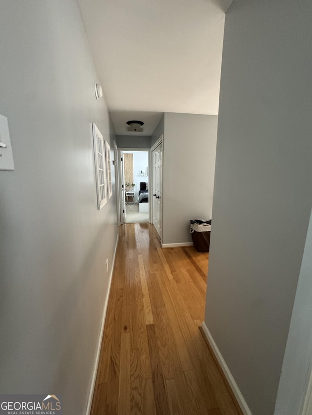 hallway featuring light wood-style flooring and baseboards