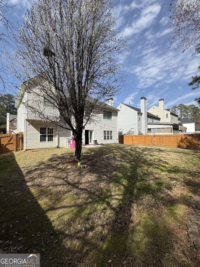 back of property with a yard and fence