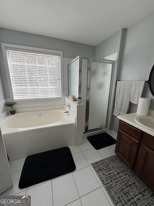 bathroom with tile patterned floors, plenty of natural light, vanity, and a garden tub