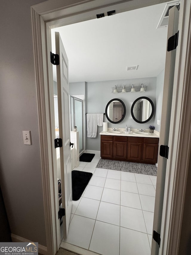 full bathroom featuring tile patterned floors, visible vents, a shower stall, and a sink