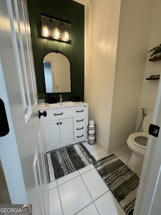 bathroom with baseboards, toilet, vanity, and tile patterned flooring