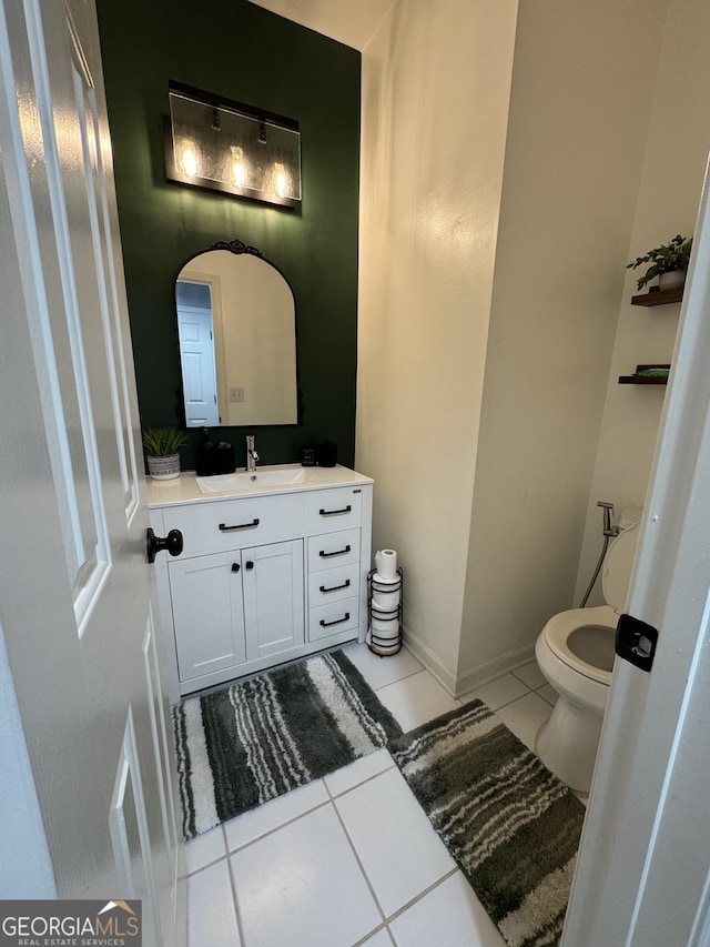 half bathroom with vanity, tile patterned floors, toilet, and baseboards