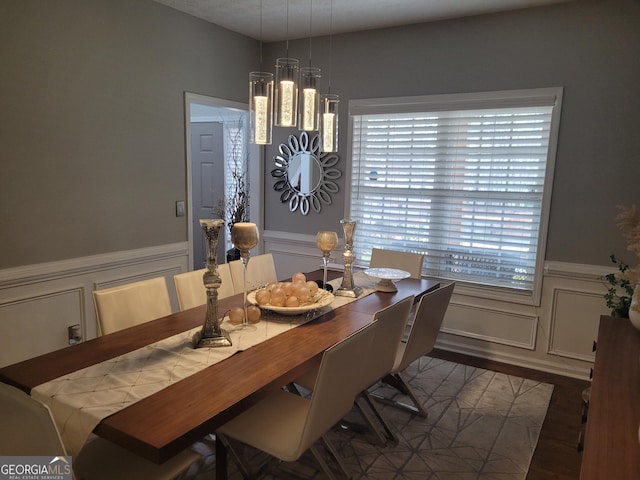 dining area featuring a wainscoted wall, a decorative wall, and wood finished floors