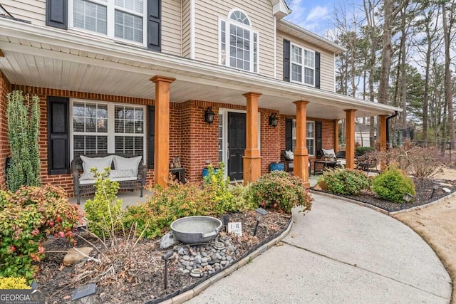 doorway to property featuring brick siding and a porch