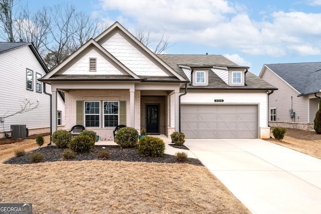 view of front of property with central AC, covered porch, concrete driveway, a garage, and brick siding