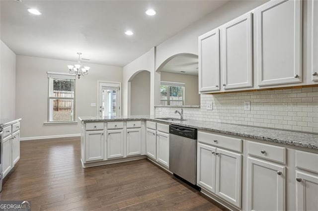 kitchen featuring backsplash, dark wood-type flooring, dishwasher, arched walkways, and a sink