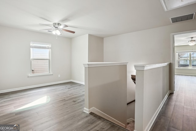 hallway featuring an upstairs landing, visible vents, attic access, and wood finished floors