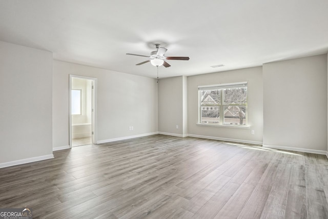 empty room featuring visible vents, baseboards, a ceiling fan, and wood finished floors