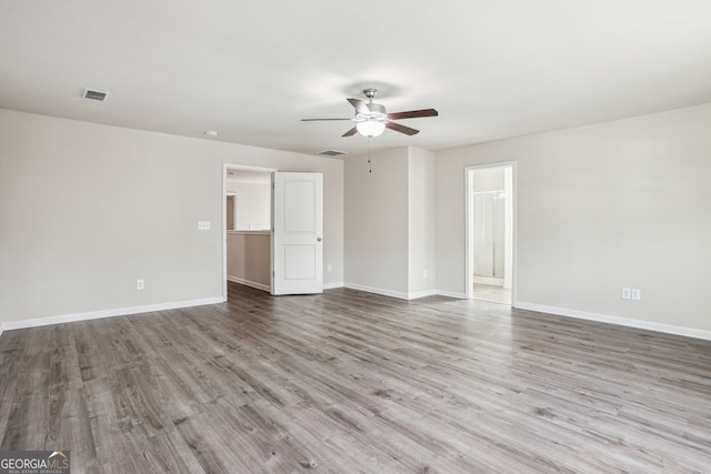 spare room with baseboards, wood finished floors, visible vents, and ceiling fan