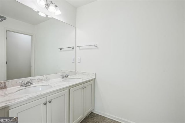 bathroom with double vanity, baseboards, and a sink