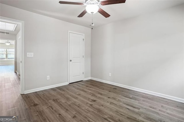 unfurnished bedroom with visible vents, baseboards, attic access, wood finished floors, and a ceiling fan