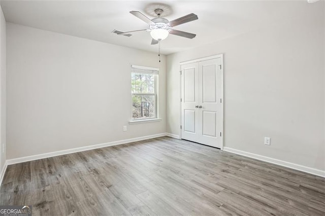 unfurnished bedroom with visible vents, a ceiling fan, wood finished floors, a closet, and baseboards