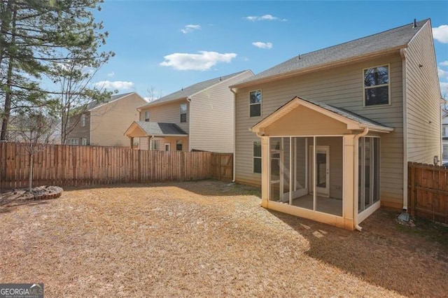 rear view of house with a fenced backyard and a sunroom