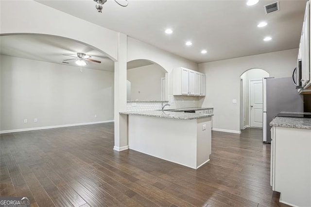 kitchen featuring visible vents, ceiling fan, arched walkways, white cabinetry, and dark wood-style flooring