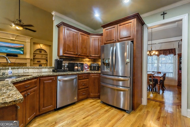 kitchen with stone counters, a sink, stainless steel appliances, crown molding, and light wood-type flooring