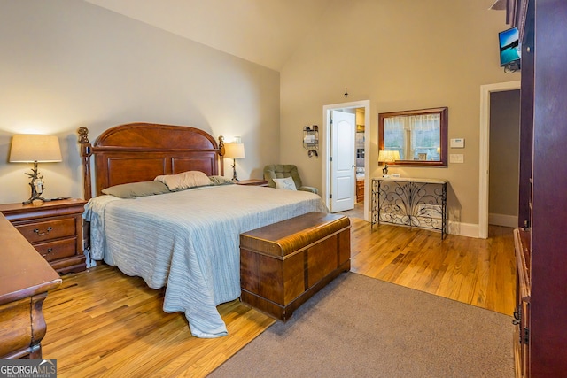 bedroom featuring light wood-style flooring, baseboards, and high vaulted ceiling