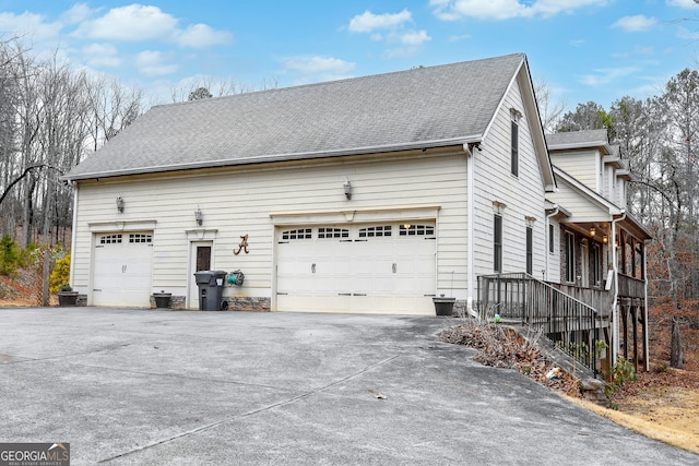 view of home's exterior featuring a garage and roof with shingles