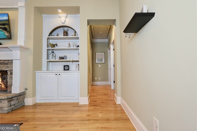 hall with built in shelves, baseboards, attic access, crown molding, and light wood-type flooring