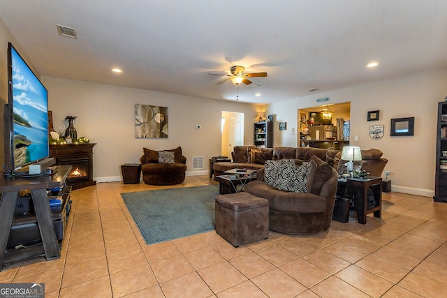 living area featuring a ceiling fan, visible vents, light tile patterned flooring, recessed lighting, and a lit fireplace