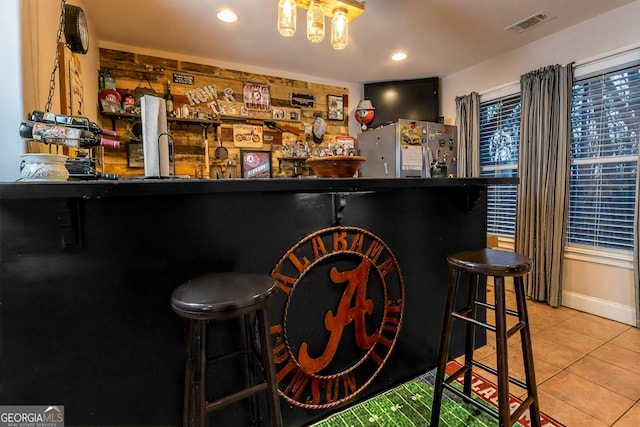 bar featuring tile patterned floors, visible vents, refrigerator, recessed lighting, and indoor bar