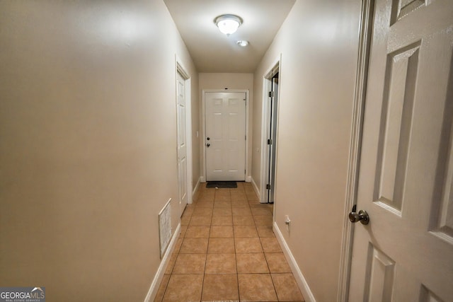 hallway featuring light tile patterned flooring, visible vents, and baseboards