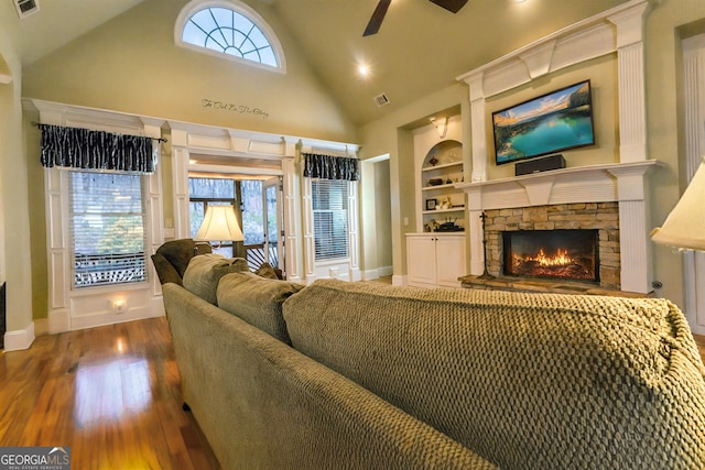 living room with built in shelves, high vaulted ceiling, a ceiling fan, wood finished floors, and a fireplace