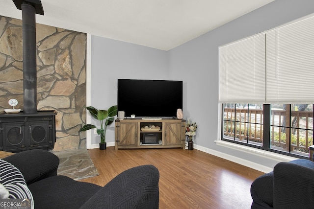 living area with a wood stove, wood finished floors, and baseboards