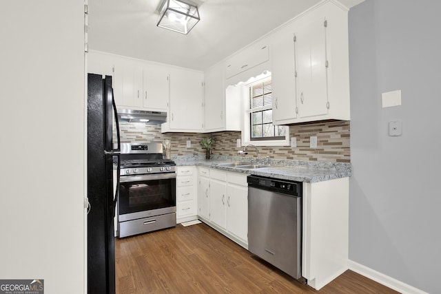 kitchen featuring dark wood-style flooring, a sink, under cabinet range hood, appliances with stainless steel finishes, and tasteful backsplash