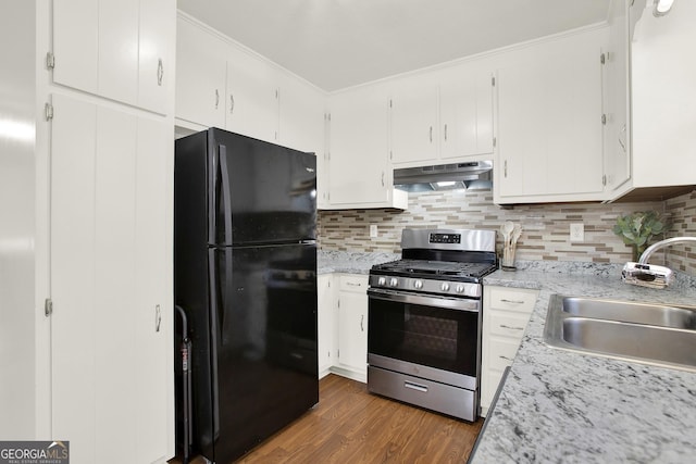 kitchen featuring dark wood-style flooring, freestanding refrigerator, a sink, under cabinet range hood, and gas range