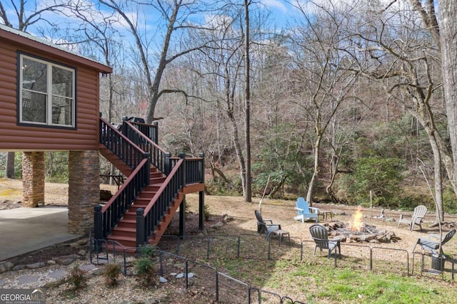 view of yard with a fire pit, fence, stairway, a deck, and a patio