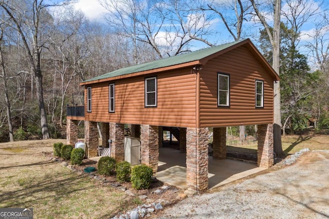 view of property exterior featuring faux log siding, metal roof, and dirt driveway