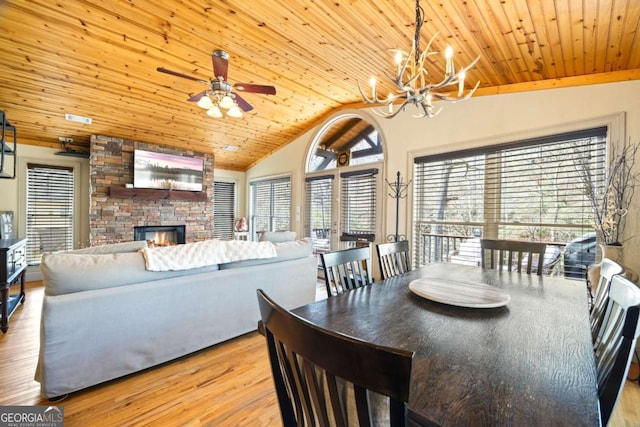 dining space featuring wood ceiling, lofted ceiling, a stone fireplace, and wood finished floors