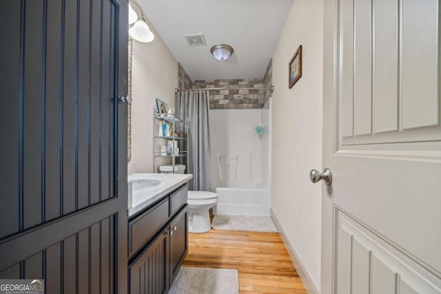 bathroom featuring visible vents, toilet, wood finished floors, shower / bath combination with curtain, and vanity