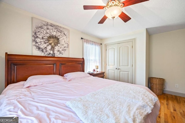 bedroom featuring a closet, a ceiling fan, baseboards, and wood finished floors