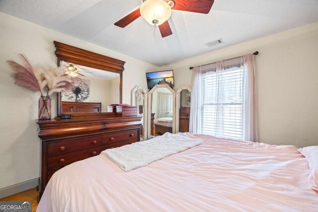 bedroom with visible vents, ceiling fan, baseboards, and wood finished floors