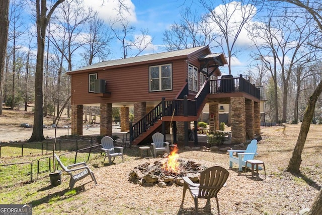 back of property featuring log veneer siding, fence, an outdoor fire pit, stairway, and a wooden deck