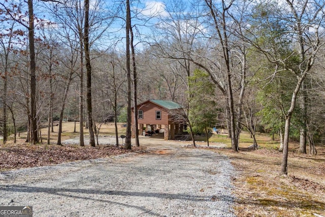 view of road with a view of trees and gravel driveway