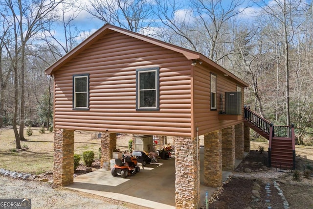 view of property exterior featuring stairs, stone siding, central AC unit, and faux log siding