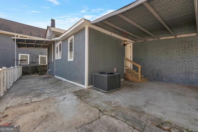 view of side of home with entry steps, a chimney, and central AC