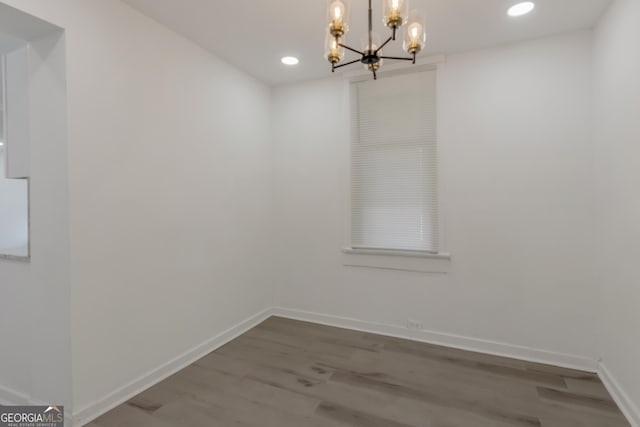 unfurnished dining area featuring recessed lighting, baseboards, an inviting chandelier, and wood finished floors