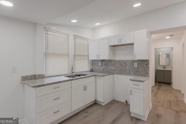 kitchen with light wood-style flooring, recessed lighting, a sink, decorative backsplash, and white cabinets