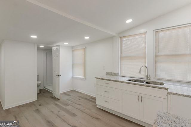 kitchen featuring a sink, light stone counters, white cabinetry, recessed lighting, and light wood finished floors