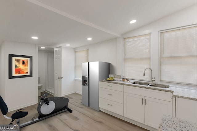 kitchen featuring light stone countertops, light wood-style flooring, recessed lighting, a sink, and white cabinets