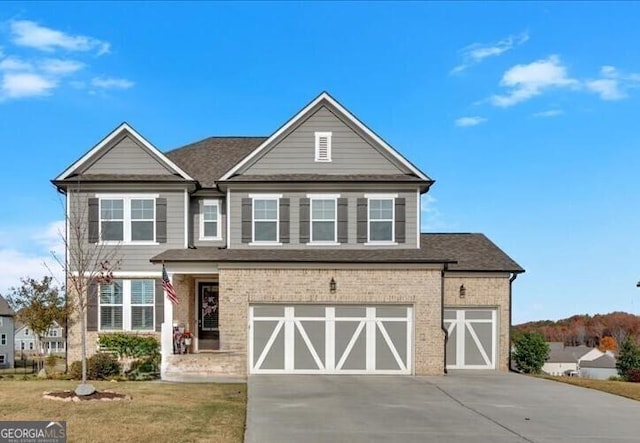 view of front facade with a front yard, driveway, roof with shingles, a garage, and brick siding