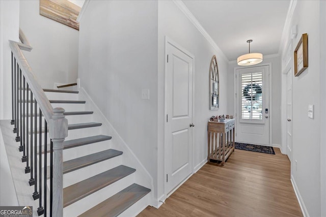 entryway with stairs, baseboards, wood finished floors, and crown molding