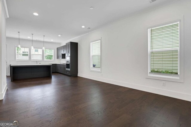 unfurnished living room featuring dark wood-style floors, recessed lighting, baseboards, and a sink