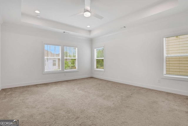 spare room featuring recessed lighting, a tray ceiling, carpet floors, and baseboards