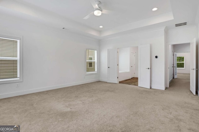 unfurnished bedroom with visible vents, a tray ceiling, recessed lighting, carpet floors, and baseboards