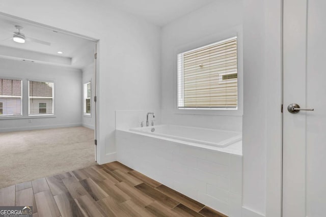 bathroom featuring a bath, wood finished floors, and baseboards